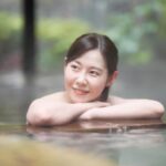 露天風呂で静かに癒される女性の姿（塩化物泉の海風に包まれる“懐かしい癒し”）