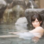 岩に囲まれた静かな露天風呂で、湯に浸かりながら“懐かしい癒し”を感じる女性の後ろ姿